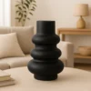 Vase Skulptural in Schwarz auf einem Wohnzimmertisch mit beiger Couch im Hintergrund